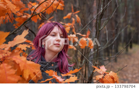 Young girl with pink hair looking up in autumn forest 133798704