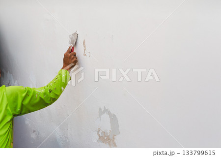 The painter scaped the wall with a trowel before painting. 133799615