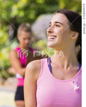 Close-up of smiling caucasian young woman with pink awareness ribbon on chest exercising in park Close-up of smiling caucasian young woman with pink awareness ribbon on chest exercising in park 133800070