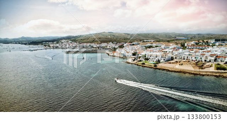 Speedboat is cutting through bay water in flat design with white red roofed houses, moored boats Speedboat is cutting through bay water in flat design with white red roofed houses, moored boats 133800153