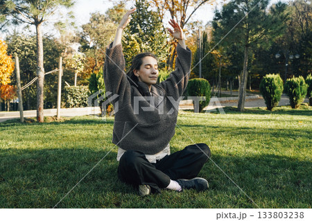 Peaceful Woman Meditating Outdoors in Sunny Autumn Park Peaceful Woman Meditating Outdoors in Sunny Autumn Park 133803238