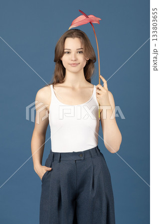 Beautiful woman with pink Anthurium flower against blue background 133803655