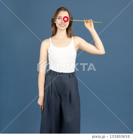 Beautiful woman covering her eye with purple flower Beautiful woman covering her eye with purple flower 133803658
