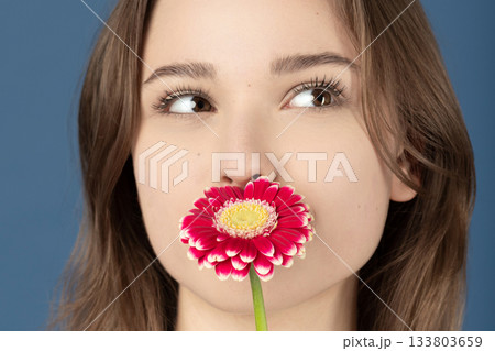 Beautiful woman covering her mouth with purple flower Beautiful woman covering her mouth with purple flower 133803659