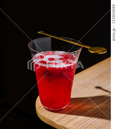 Refreshing red drink served in a stylish glass on a wooden table 133804089