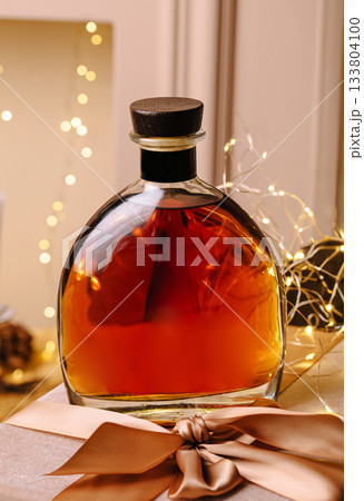 Elegant glass bottle of amber liquor on a festive table with decorations 133804100