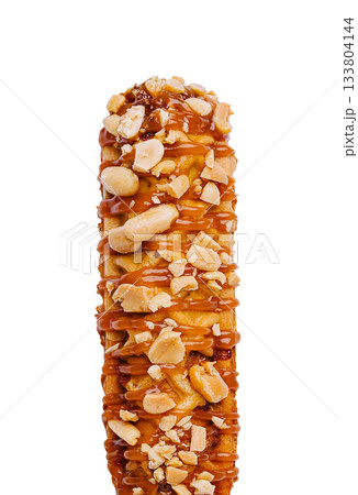 Delicious caramel-coated corn dog snack topped with crunchy peanuts 133804144