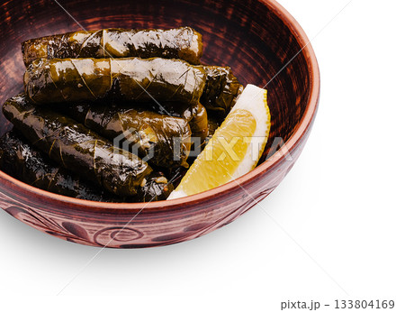 Delicious stuffed grape leaves served in a wooden bowl with lemon slice 133804169