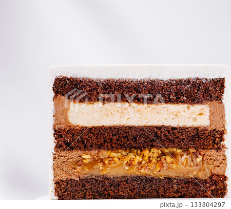 Delicious layered chocolate cake with creamy filling and nuts Delicious layered chocolate cake with creamy filling and nuts 133804297