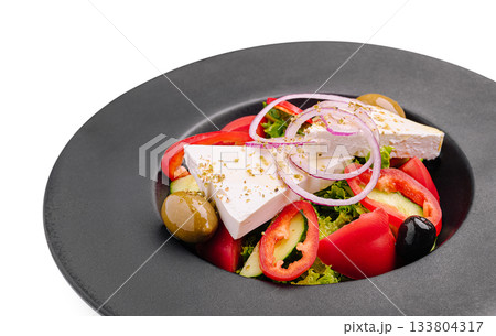 Fresh Greek salad with feta cheese and olives on a black plate 133804317