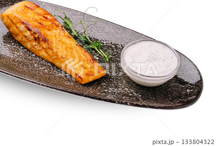 Grilled salmon fillet served with creamy sauce on a stylish plate Grilled salmon fillet served with creamy sauce on a stylish plate 133804322