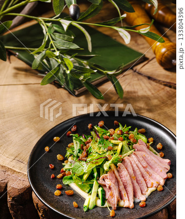 Fresh salad with sliced meat on a rustic wooden table in a cozy setting 133804396