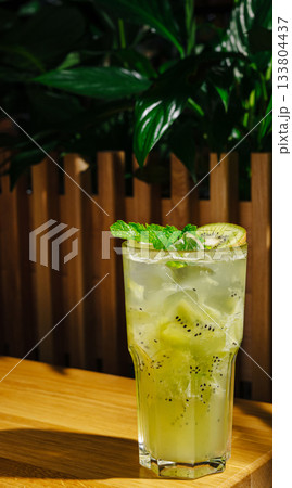 Refreshing cocktail with kiwi and mint served in a glass on a wooden table Refreshing cocktail with kiwi and mint served in a glass on a wooden table 133804437