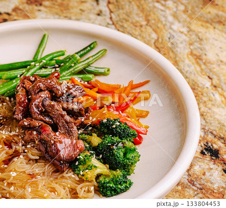 Colorful plate of stir-fried noodles with beef and fresh vegetables served 133804453