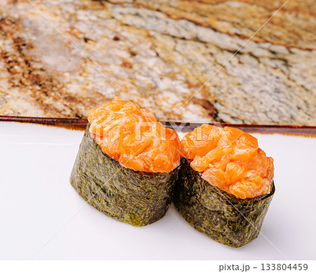 Two pieces of sushi with salmon topping on a white plate 133804459