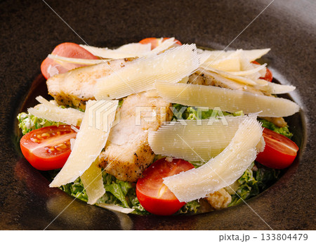 Grilled fish salad with cherry tomatoes and cheese on a dark plate Grilled fish salad with cherry tomatoes and cheese on a dark plate 133804479