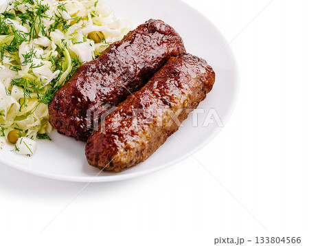 Delicious grilled kebabs served with fresh cabbage salad on a white plate 133804566
