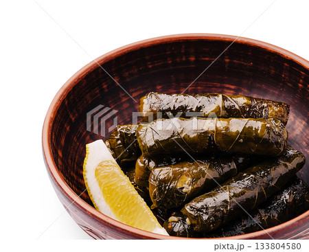 Savory grape leaves stuffed with rice and herbs served in a bowl 133804580