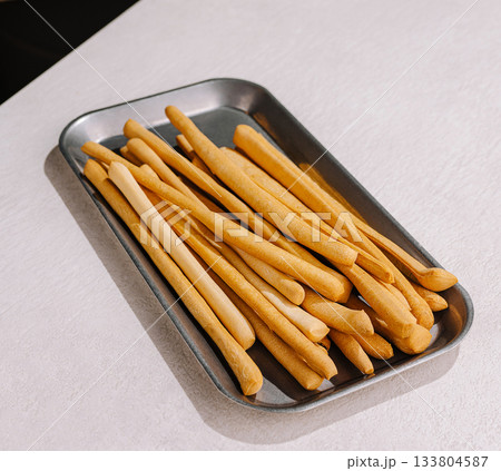 Baked breadsticks served on a metal tray ready for enjoyment at a meal 133804587