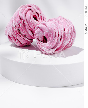 Delicate pink meringues resting on a white dessert display Delicate pink meringues resting on a white dessert display 133804615