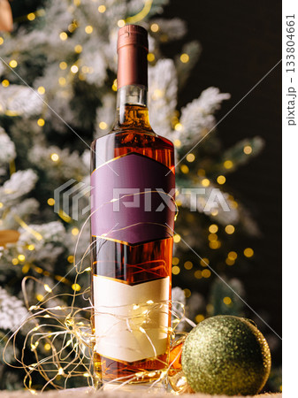 Holiday spirit shines through a decorative bottle of liquor near a festive tree 133804661