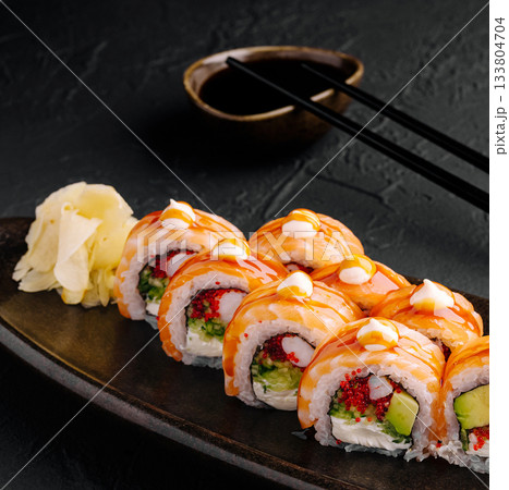 Delicious sushi rolls served with ginger and soy sauce on a black plate 133804704