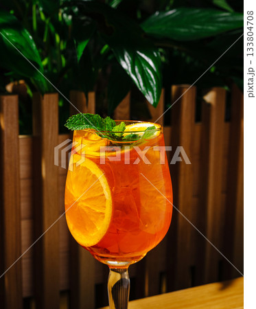 Refreshing citrus drink served in elegant glass among greenery Refreshing citrus drink served in elegant glass among greenery 133804708