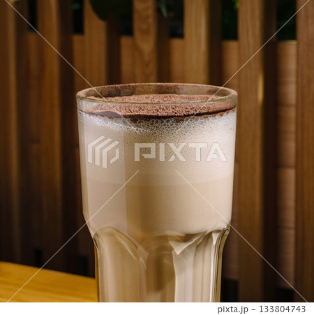 Delicious coffee latte topped with chocolate foam in a cozy cafe setting Delicious coffee latte topped with chocolate foam in a cozy cafe setting 133804743
