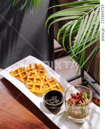 Delicious waffles served with ice cream and sauce in a tropical setting Delicious waffles served with ice cream and sauce in a tropical setting 133804795