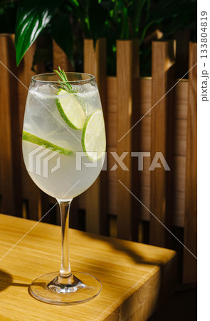 Refreshing drink with lime slices served in a glass on a wooden table 133804819