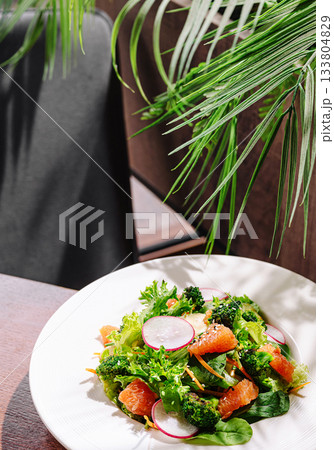 Fresh salad with greens, broccoli, and oranges served in a cozy setting Fresh salad with greens, broccoli, and oranges served in a cozy setting 133804829