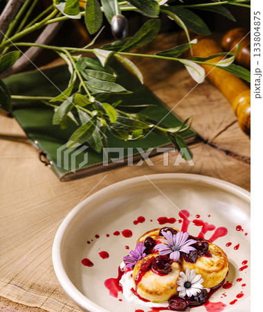 Delicious dessert with flowers and berry sauce on a rustic wooden table Delicious dessert with flowers and berry sauce on a rustic wooden table 133804875