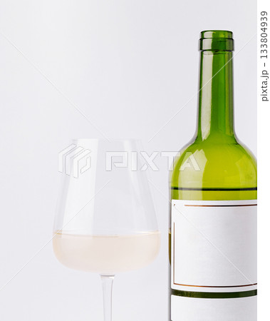 Enjoying a glass of white wine next to a bottle on a white background Enjoying a glass of white wine next to a bottle on a white background 133804939