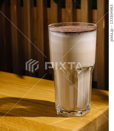 Delicious creamy drink served in a tall glass on a wooden table Delicious creamy drink served in a tall glass on a wooden table 133804963