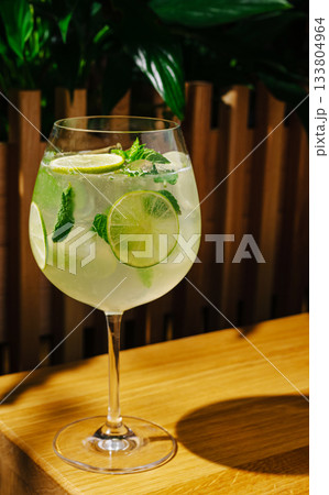 Refreshing cocktail with lime and mint in a glass on wooden table Refreshing cocktail with lime and mint in a glass on wooden table 133804964