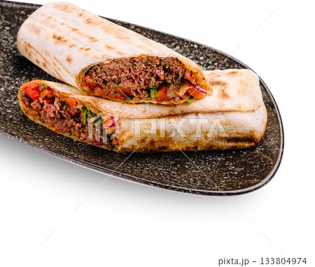 Savory beef wraps with fresh vegetables served on a dark platter Savory beef wraps with fresh vegetables served on a dark platter 133804974