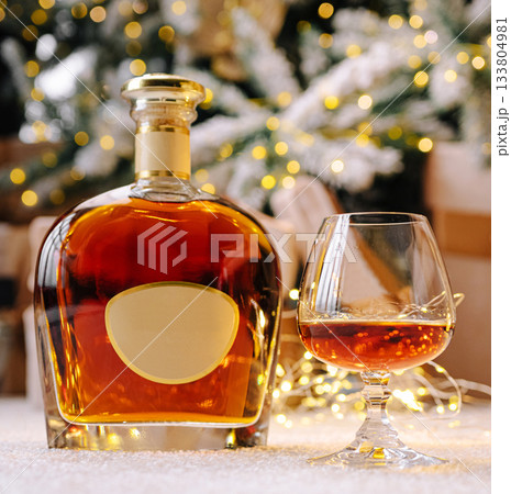 Premium whiskey bottle and glass displayed among holiday decorations 133804981