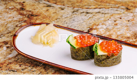 Delicious sushi rolls topped with fish roe and garnished with ginger 133805004