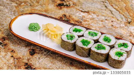 Sushi rolls with vibrant green filling served on a sleek platter Sushi rolls with vibrant green filling served on a sleek platter 133805035
