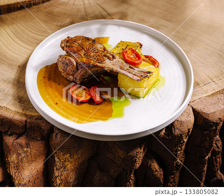 Savory grilled lamb chops served with roasted vegetables on a wooden table Savory grilled lamb chops served with roasted vegetables on a wooden table 133805082