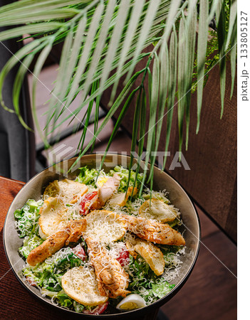 Fresh salad topped with chicken and cheese on wooden table with green leaves Fresh salad topped with chicken and cheese on wooden table with green leaves 133805127