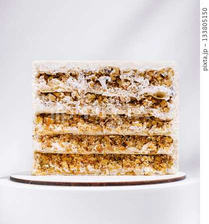 Layers of creamy nut cake on a wooden board in bright light Layers of creamy nut cake on a wooden board in bright light 133805150