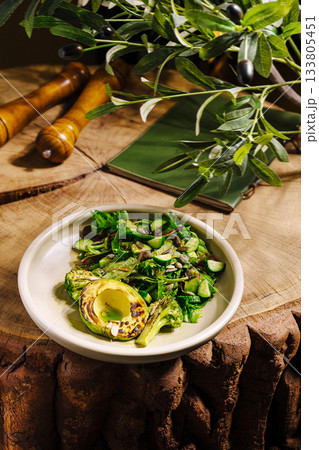 Grilled vegetables and avocado served on wooden table with olive branches 133805451