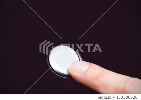 White finger pressing a small white button 133806620