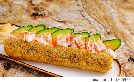A sushi roll featuring a crispy exterior is presented on a plate A sushi roll featuring a crispy exterior is presented on a plate 133806978