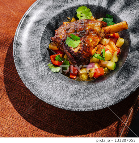 Deliciously cooked lamb shank served with fresh vegetable medley 133807055