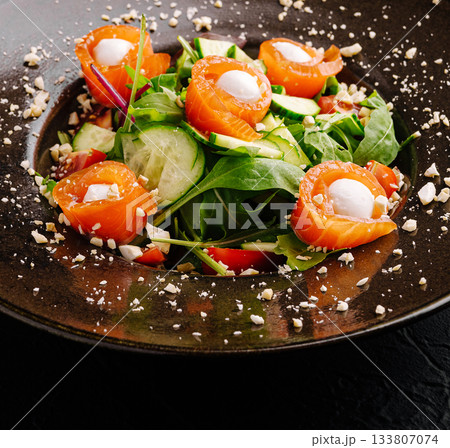 Fresh salmon salad with greens and vegetables on a dark plate Fresh salmon salad with greens and vegetables on a dark plate 133807074