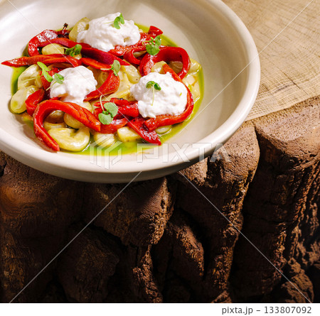 Tasty dish with red peppers, creamy topping, and fresh herbs 133807092