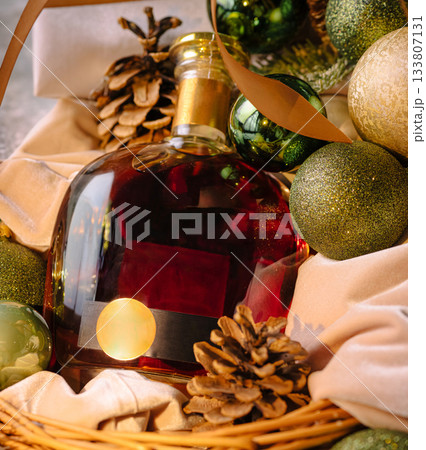Elegant holiday gift basket with wine, ornaments, and pinecones 133807131