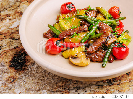 Colorful stir-fried vegetables and beef served on a marble table 133807135